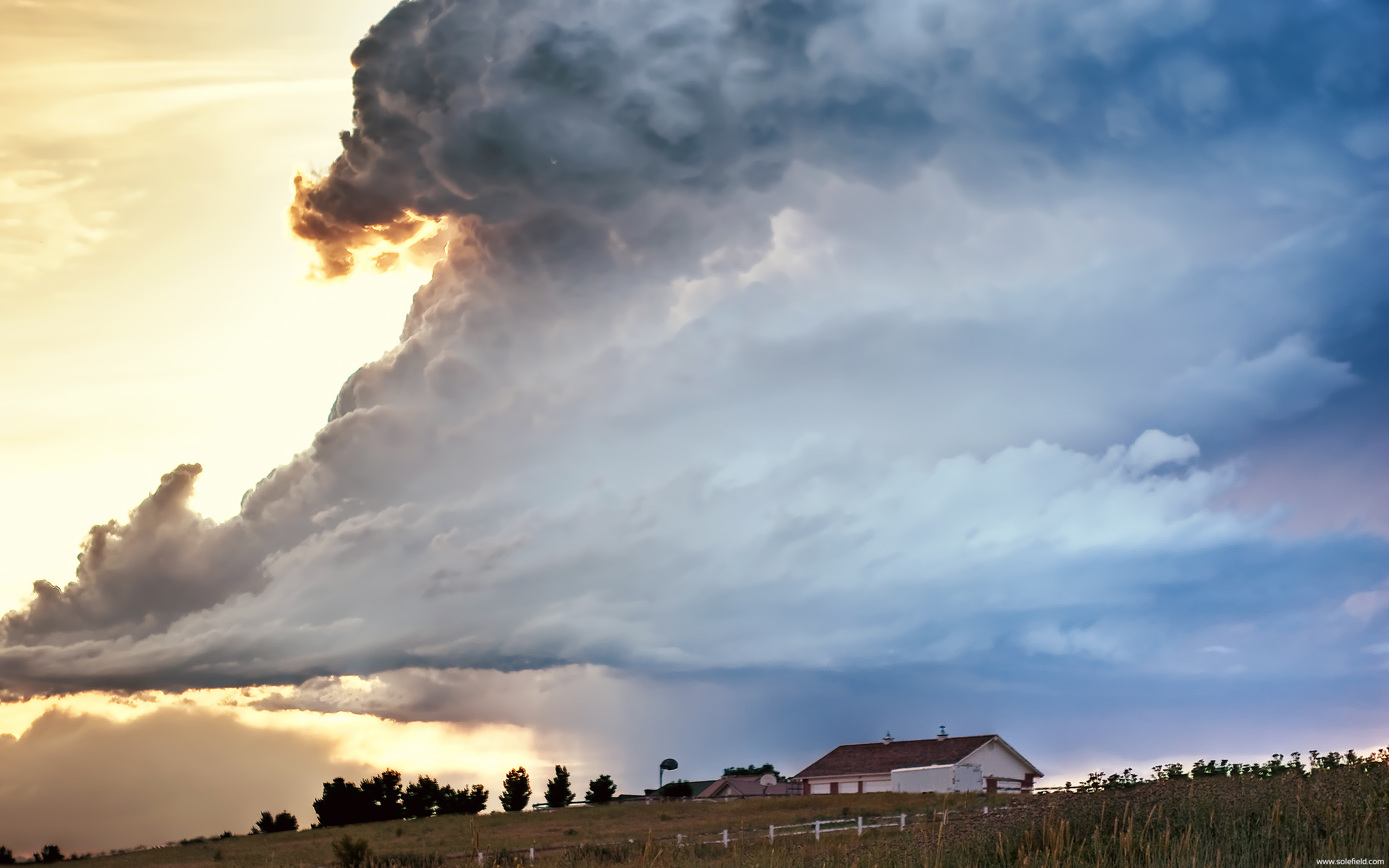 Dramatic cloud during sunset over farmhouse