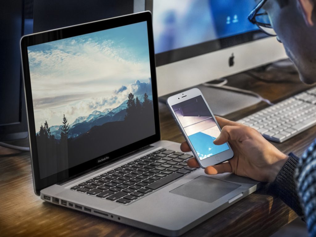 Man viewing iphone and desktop wallpaper